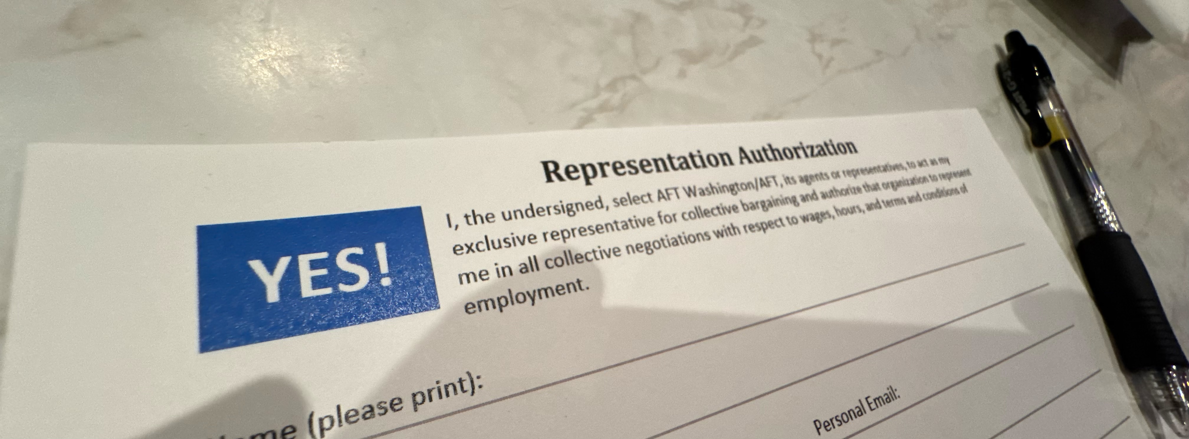 An AFT representation authorization card on a white marble table with a pen sitting next to it.
